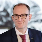 Portrait von Fabian Schmid, Geschäftsführer der Denkströme Gruppe, im Business-Outfit mit roter Krawatte – moderne Führungspersönlichkeit im Bereich Kommunikation und Transformation